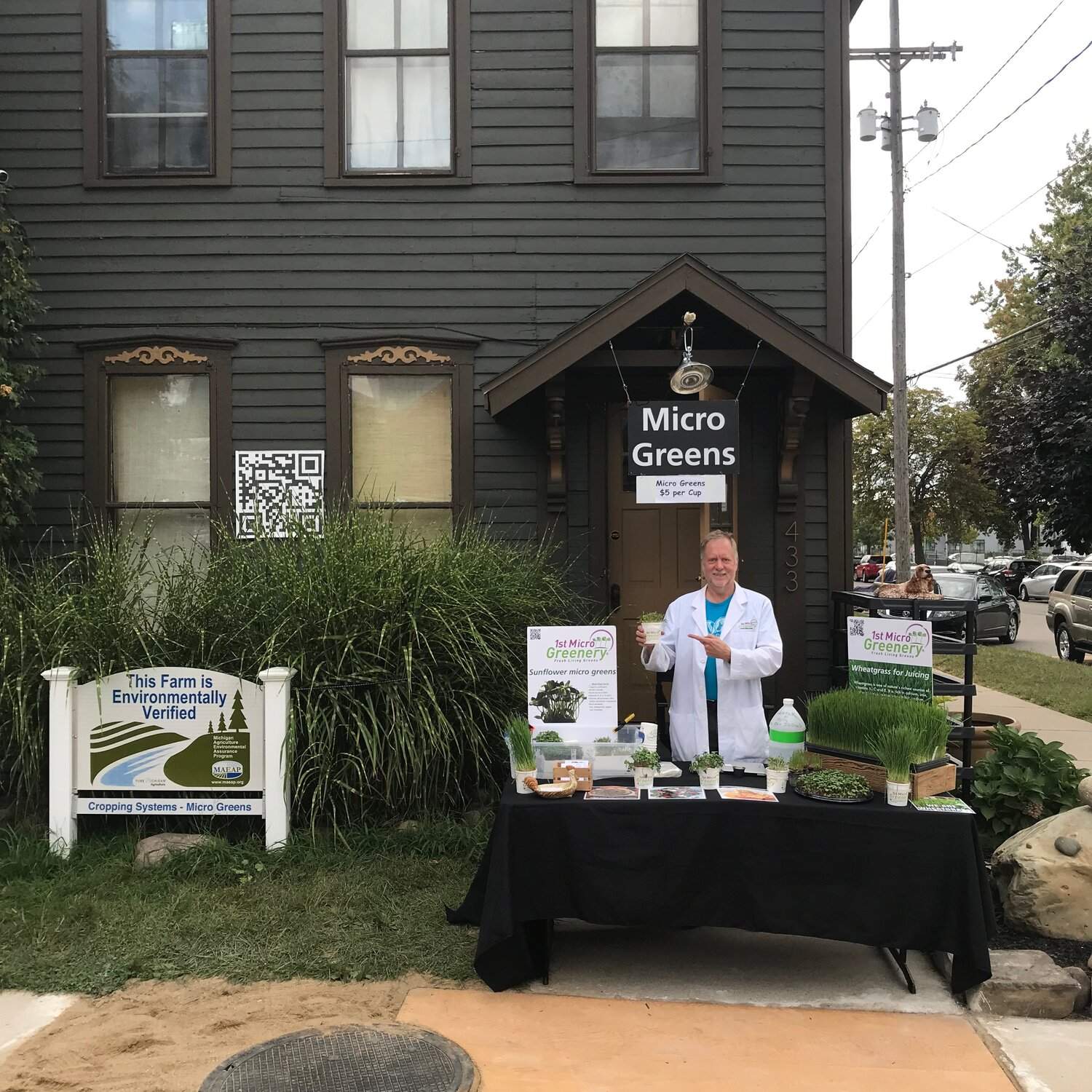 Person standing behind a table with micro greens and promotional materials in front of 1st micro greenery.