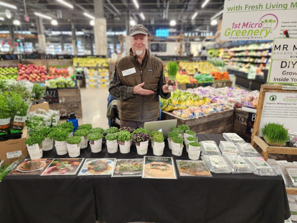 Chris Huntoon standing behind a table with micro greens and Mr Micro in a grocery store